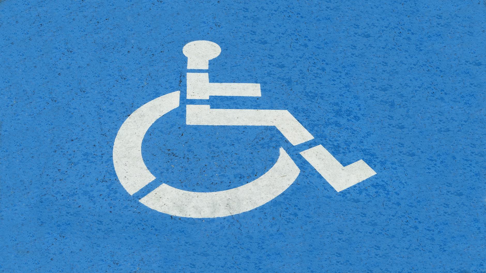 Close-up of a white handicap parking symbol on blue pavement, symbolizing accessibility and safety.