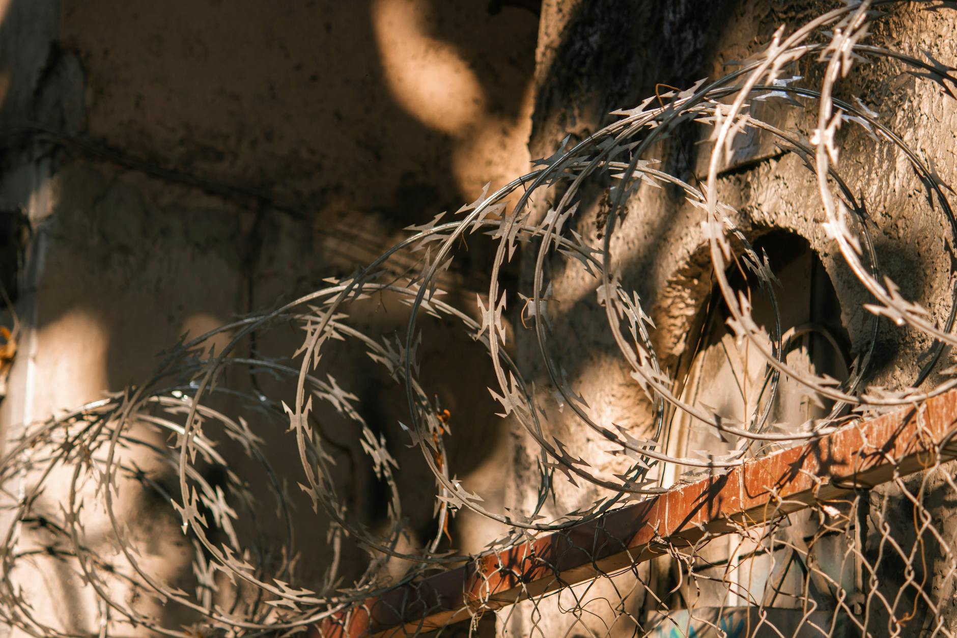 Close-up of barbed wire casting shadows on an old wall, creating dramatic effects.