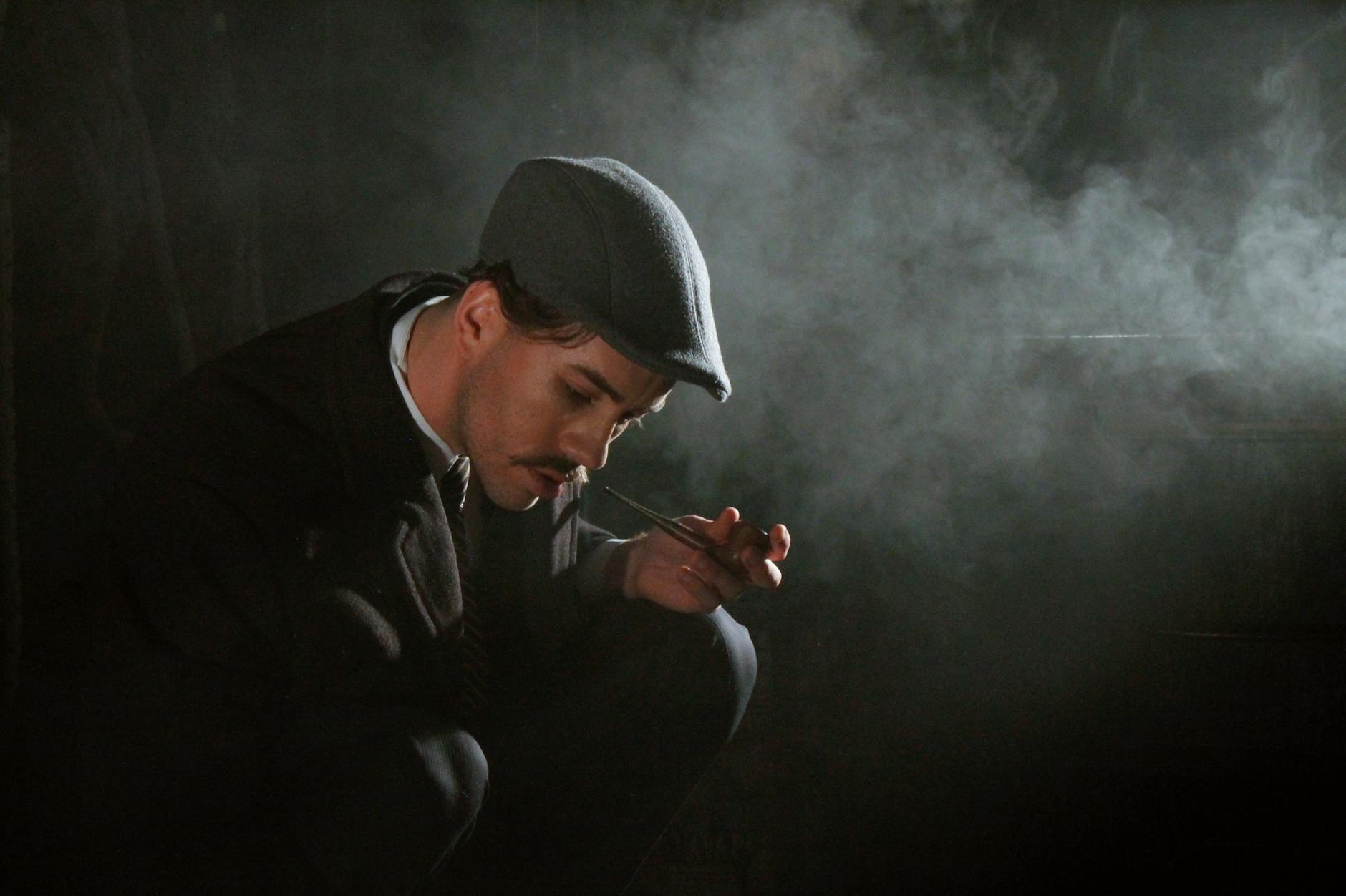 A man in vintage attire smokes a pipe in a dark, moody setting with swirling smoke.