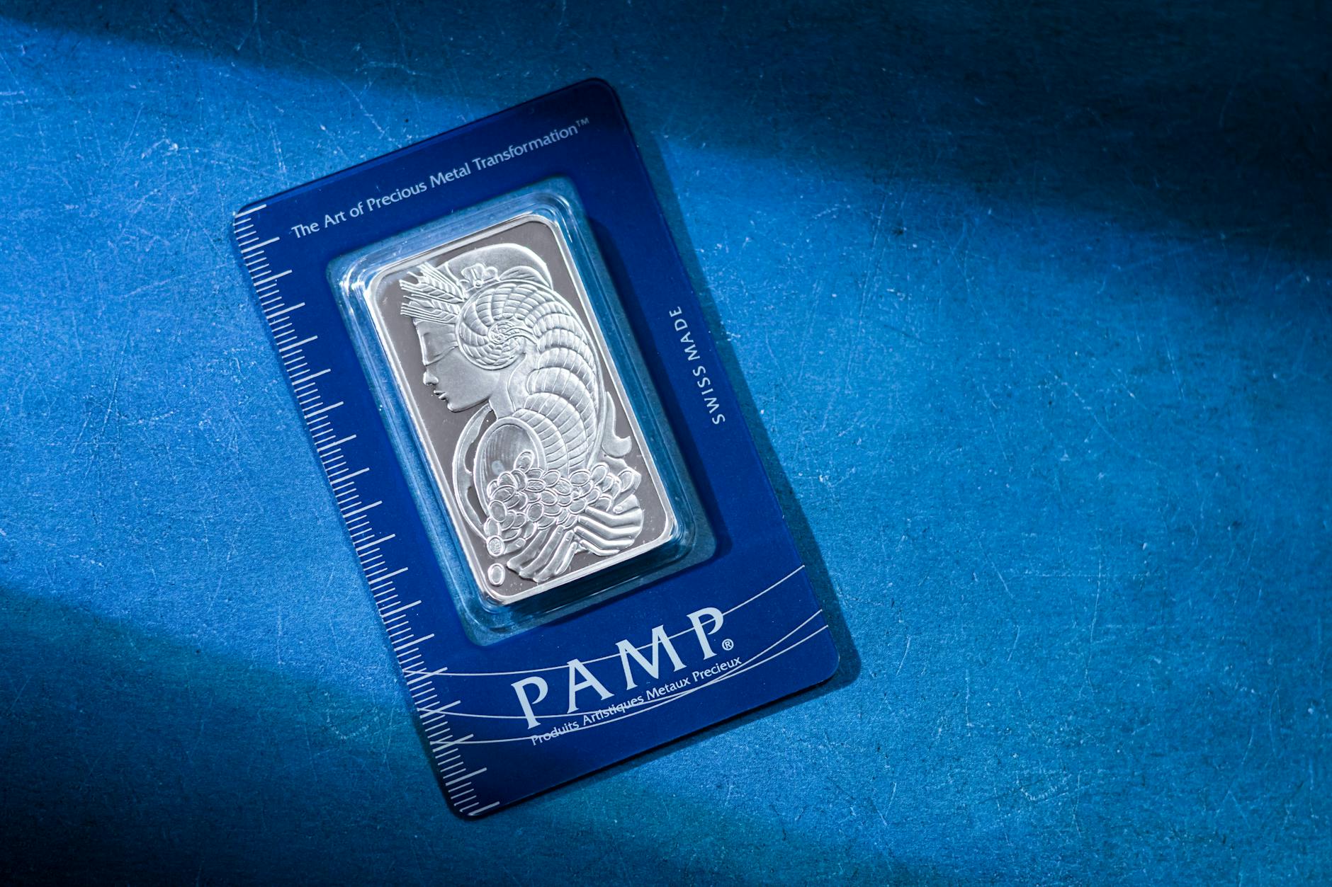 High-quality silver PAMP bar on a striking blue background, emphasizing luxury and security.