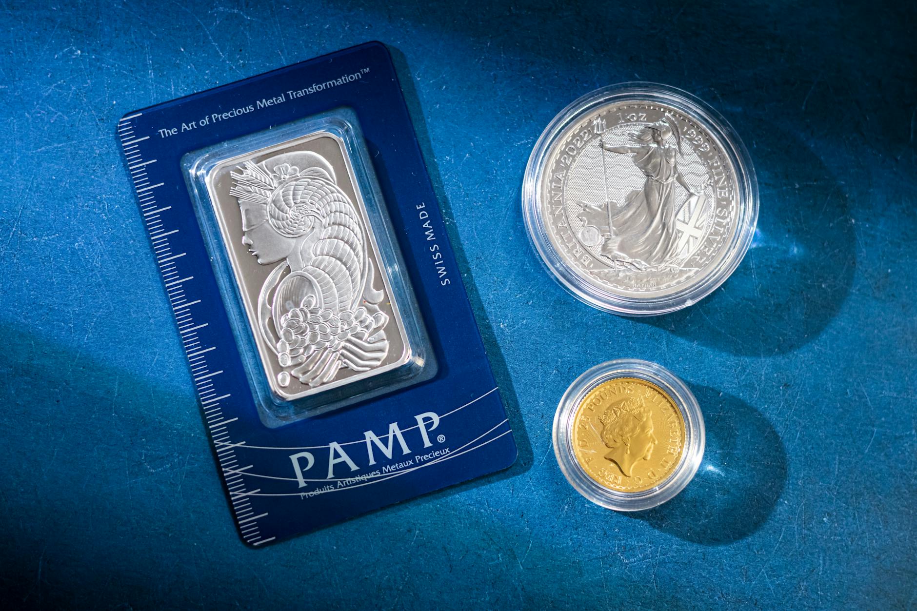 Silver bar and coins on blue surface, highlighting investment and collectible value.