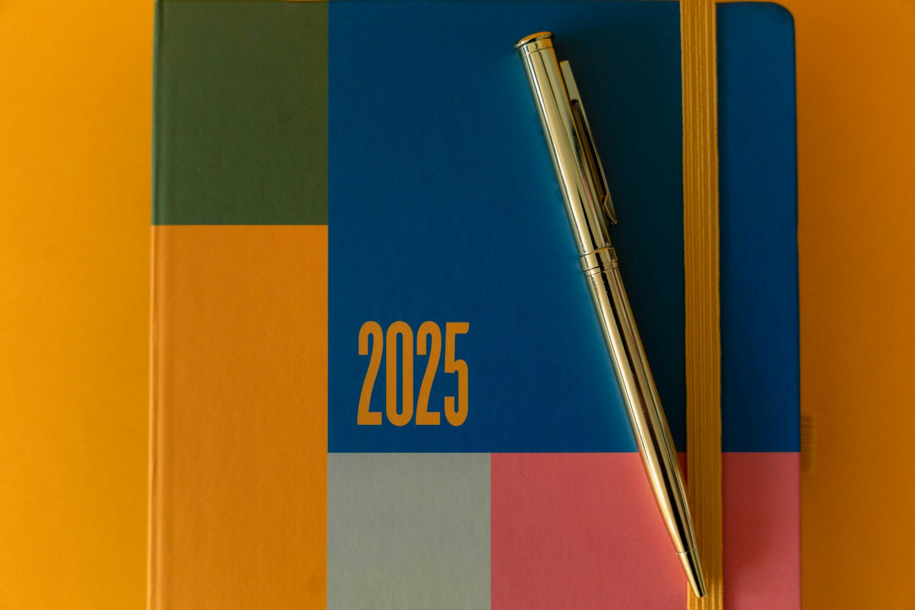 A vibrant 2025 planner with a pen on a colorful backdrop, ideal for organization.