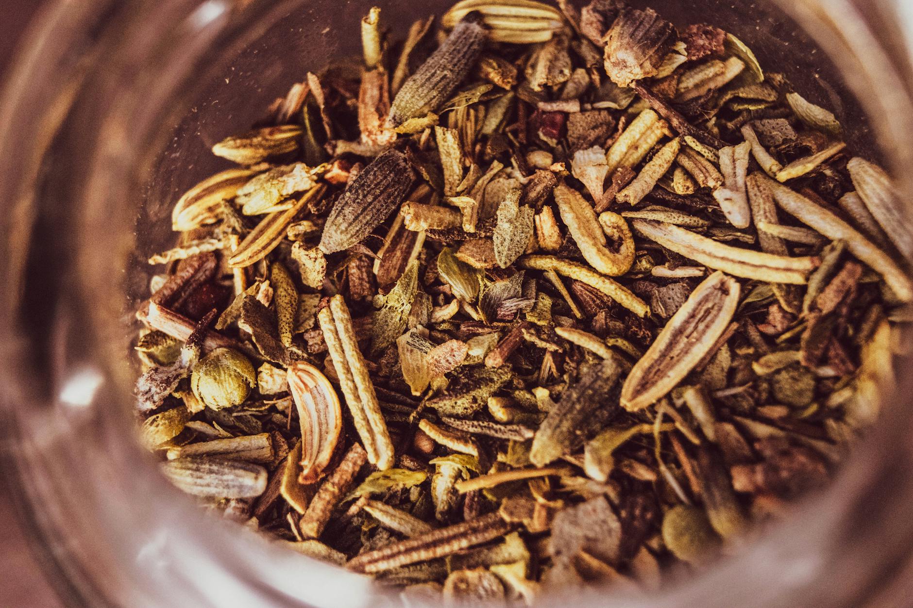 A macro shot of an assortment of dried herbs and spices in a jar, showcasing texture and color.