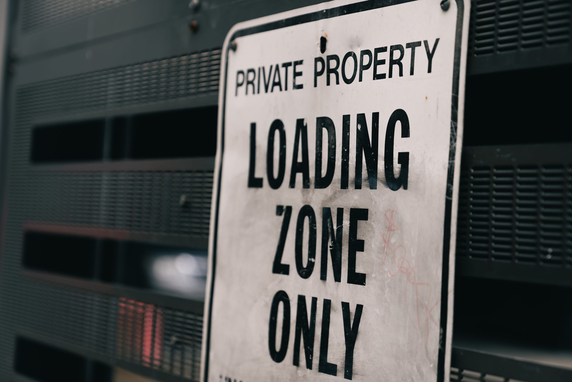 Close-up of a private property loading zone only sign with urban backdrop.