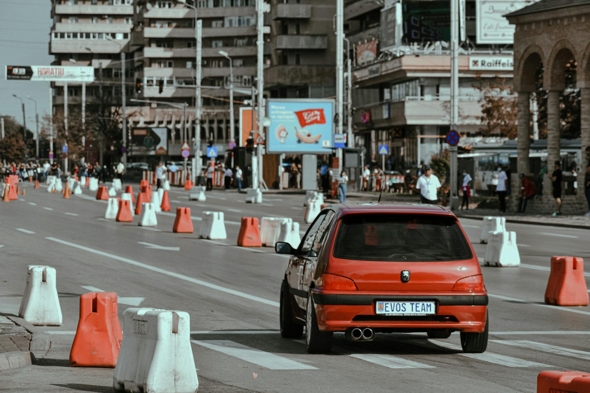 Small red car driving fast on closed city street while taking part in urban rally