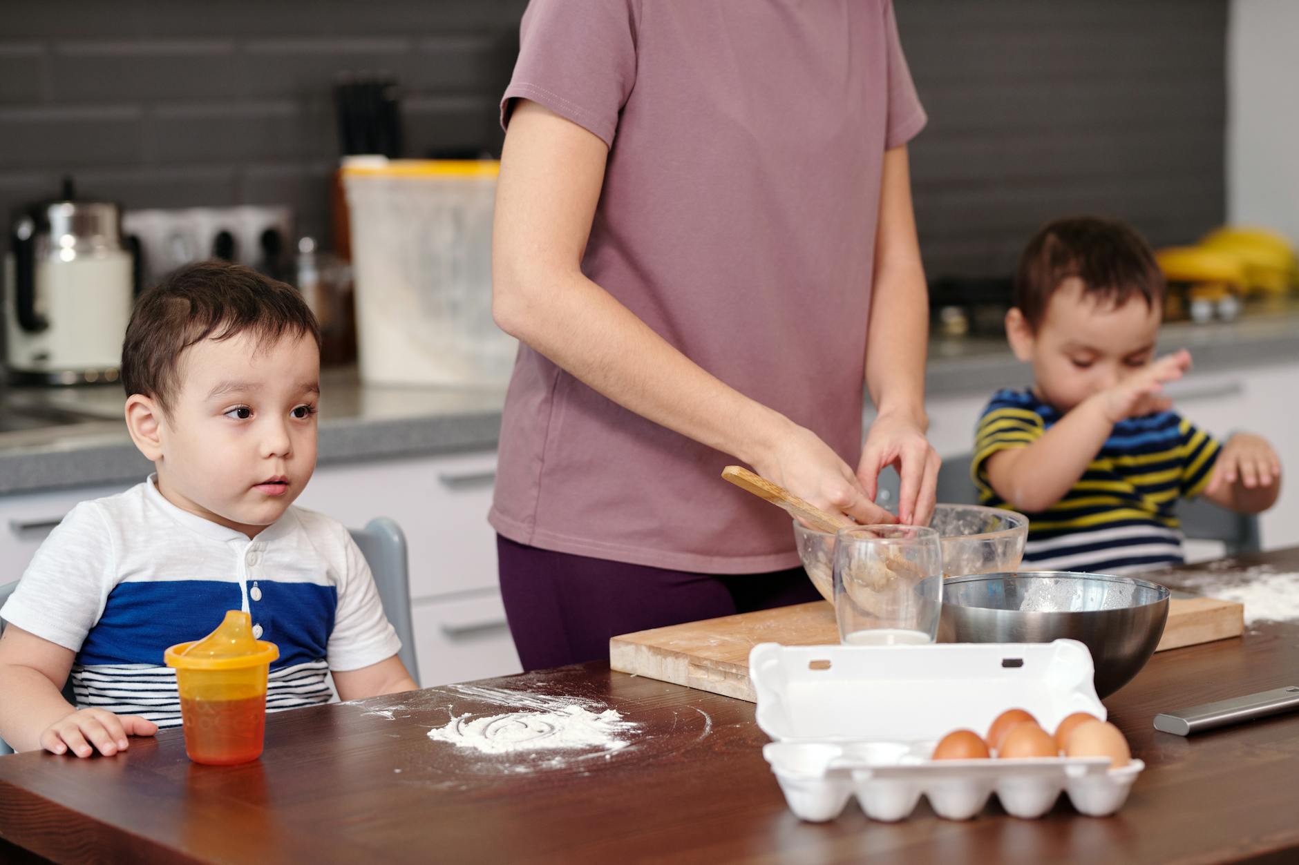 A mother and her young sons baking together, preparing dough and enjoying family time.