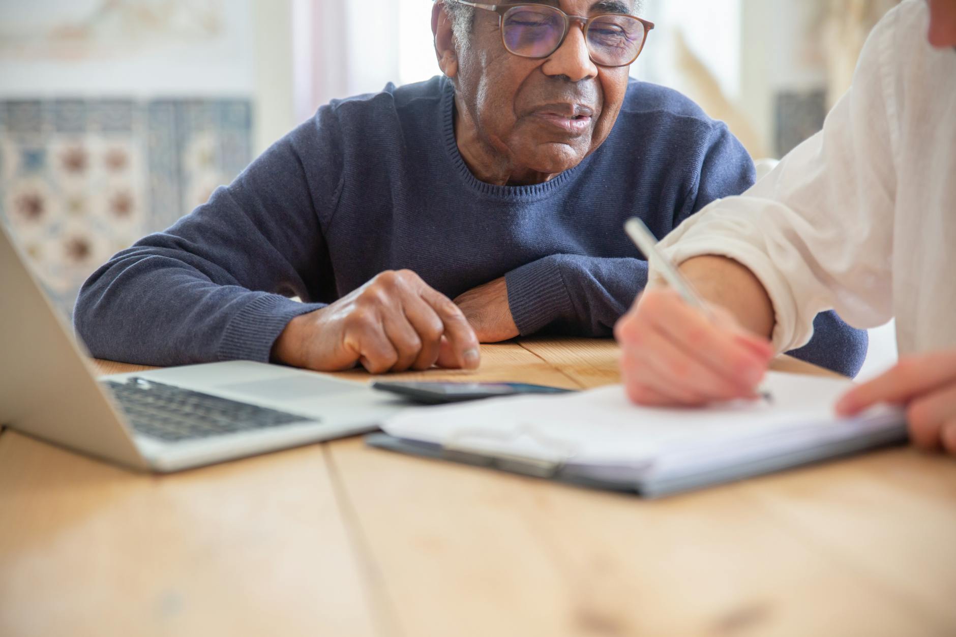 Senior African American man receiving assistance with paperwork at home.