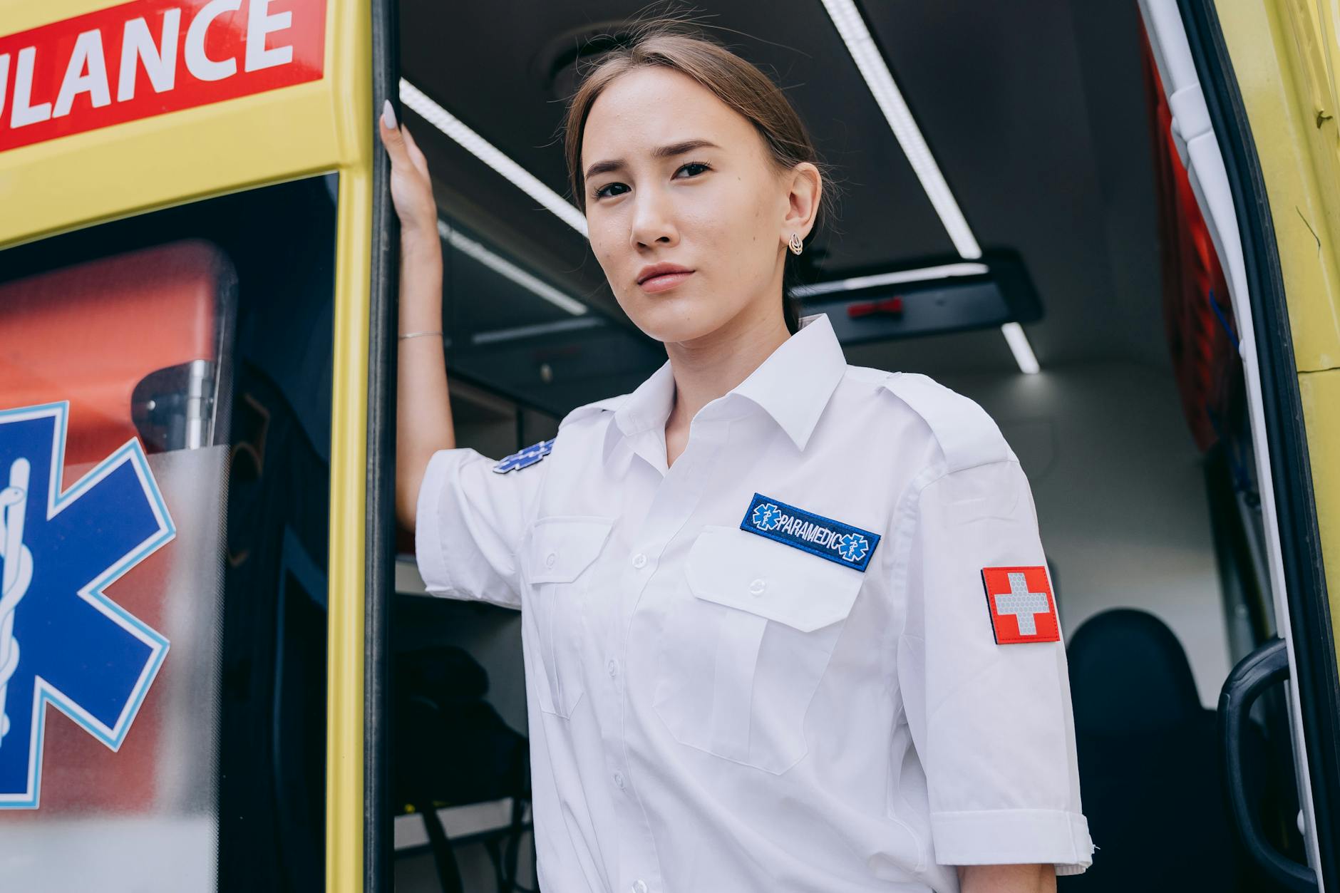 Young paramedic stands confidently by an ambulance, ready for emergency response.